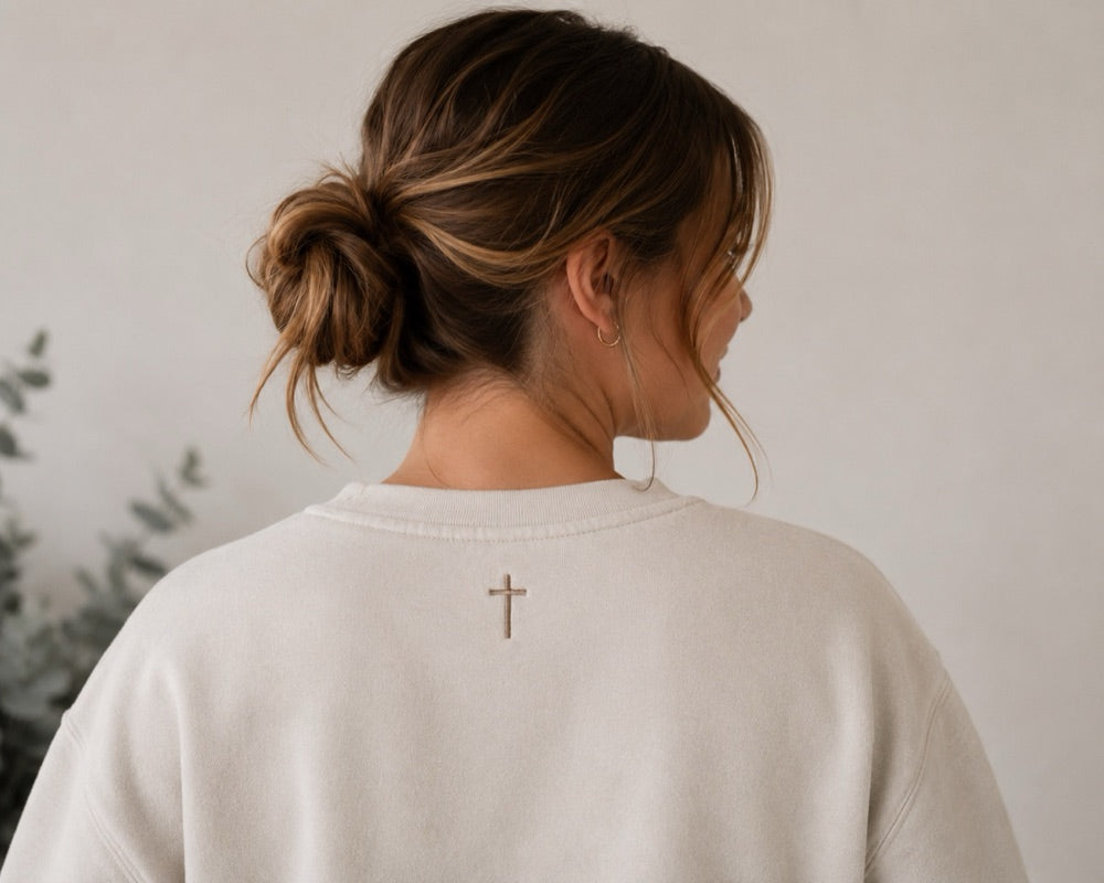 Back of the cream crewneck with the embroidered signature cross